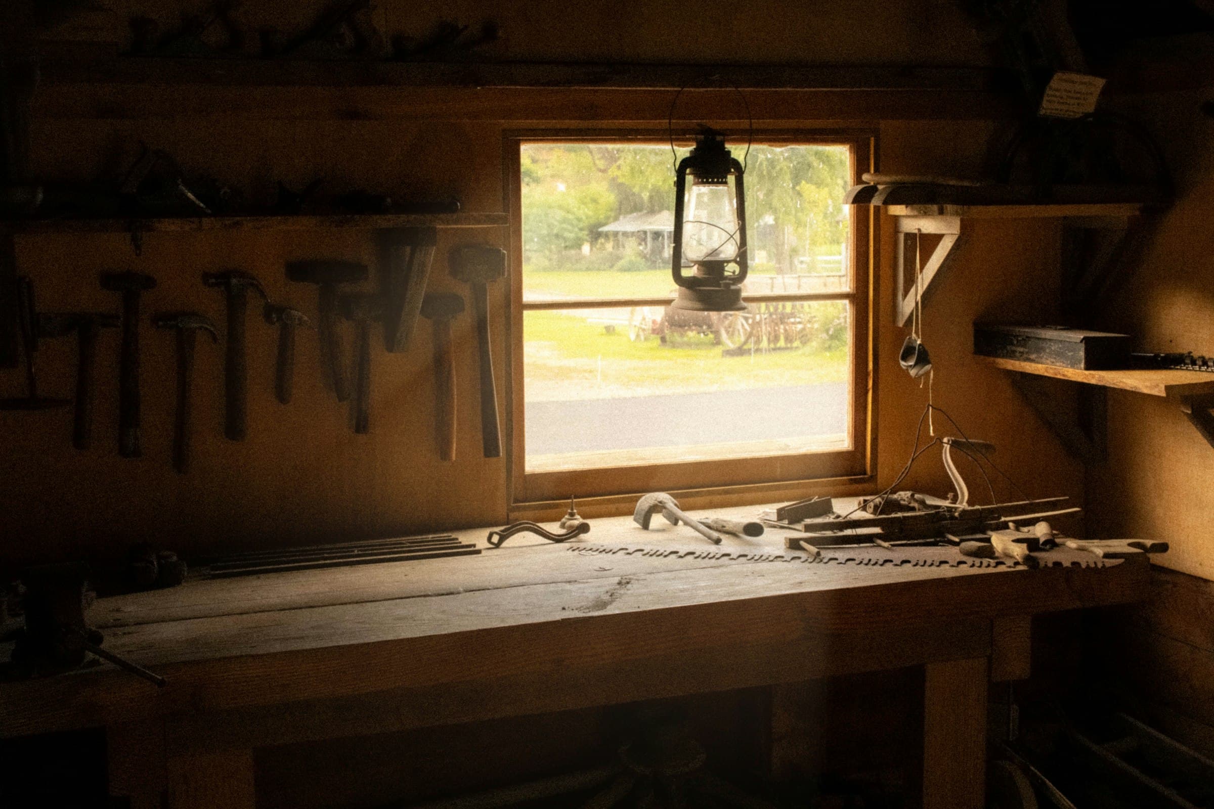 A workbench and tools under a window in a rustic workshop