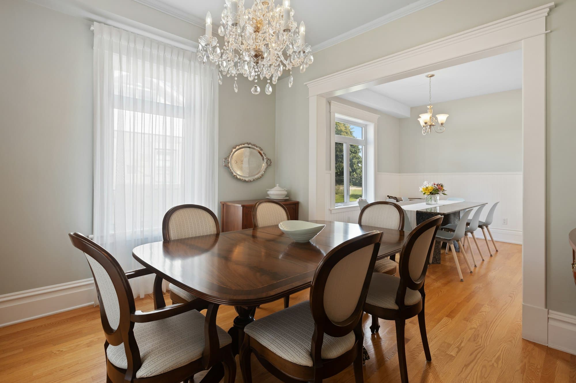 A dining table and chairs under a hanging chandelier