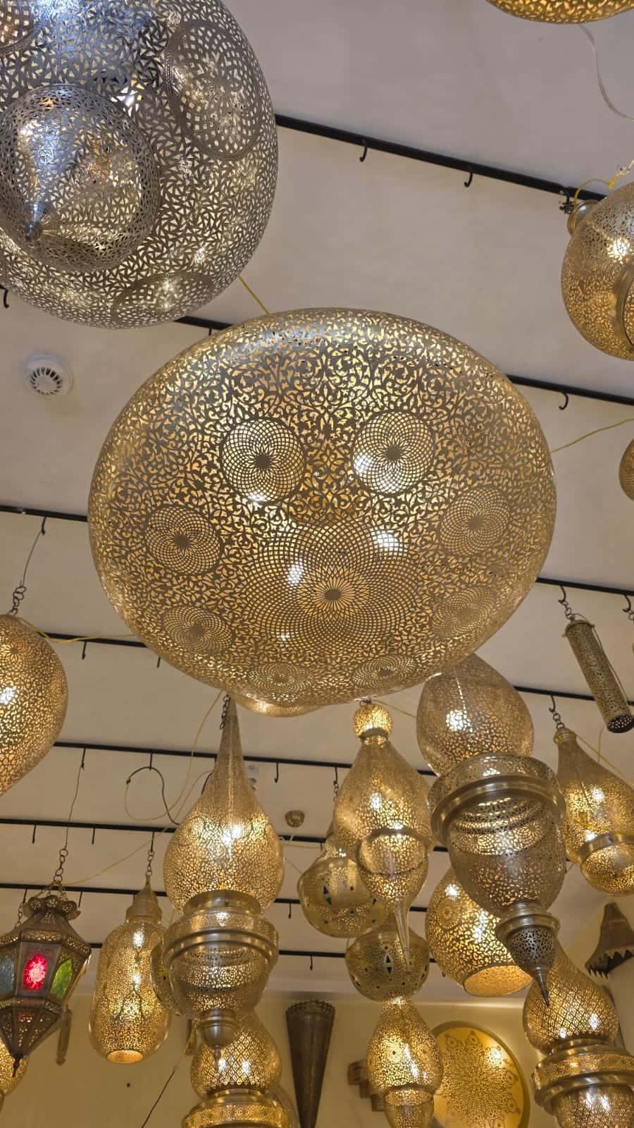 Round hand-pierced brass dome pendant, lit, among other lamps in the showroom