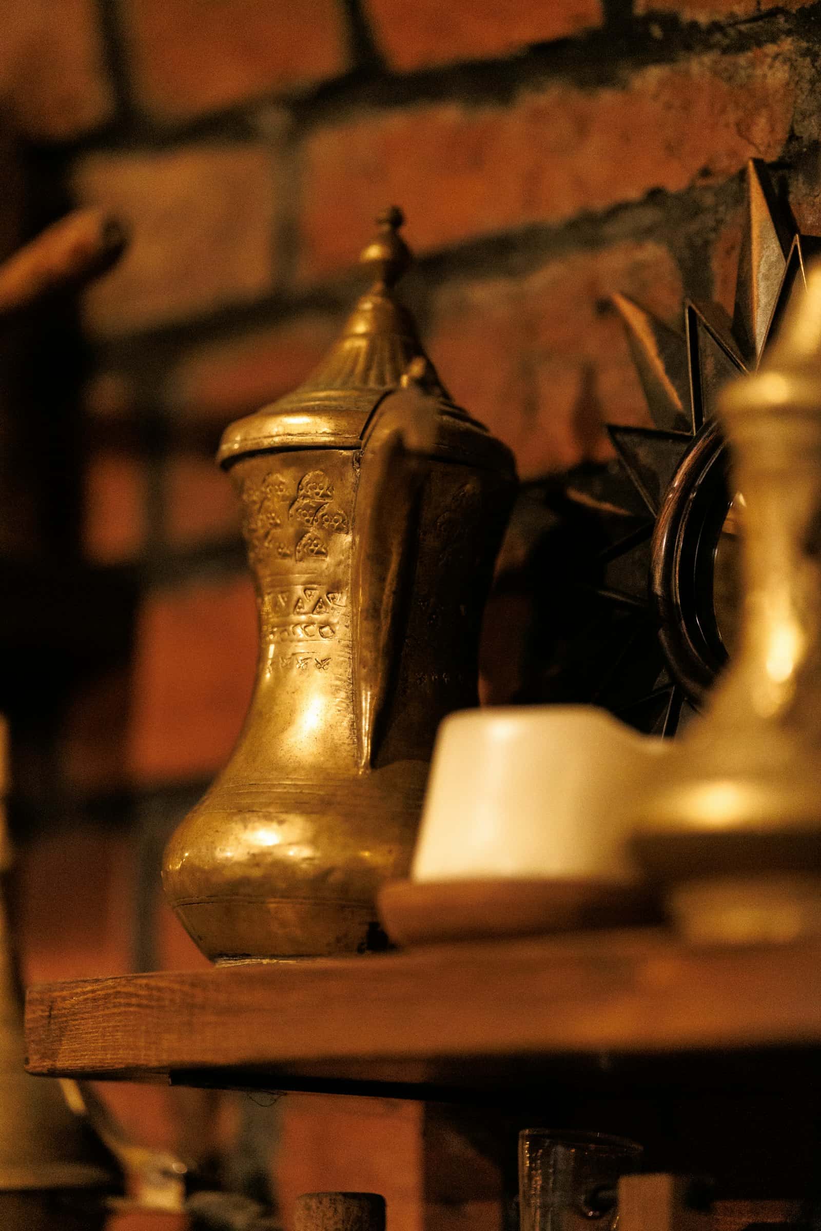 An old brass coffee pot with an engraved pattern